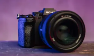 Czarna lustrzanka z kamerą Sony, z obiektywem na pierwszym planie, oświetlona niebieskim i fioletowym światłem.