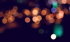 Rozmyte, okrągłe światła w różnych kolorach na ciemnym tle.