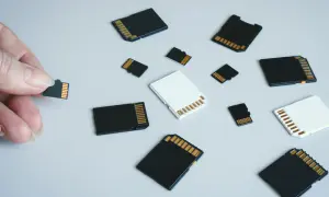 Dłoń trzyma kartę pamięci, obok leżą różne karty SD i microSD. Jaka karta pamięci do aparatu będzie najlepsza?