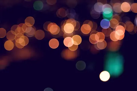 Rozmyte, okrągłe światła w różnych kolorach na ciemnym tle.