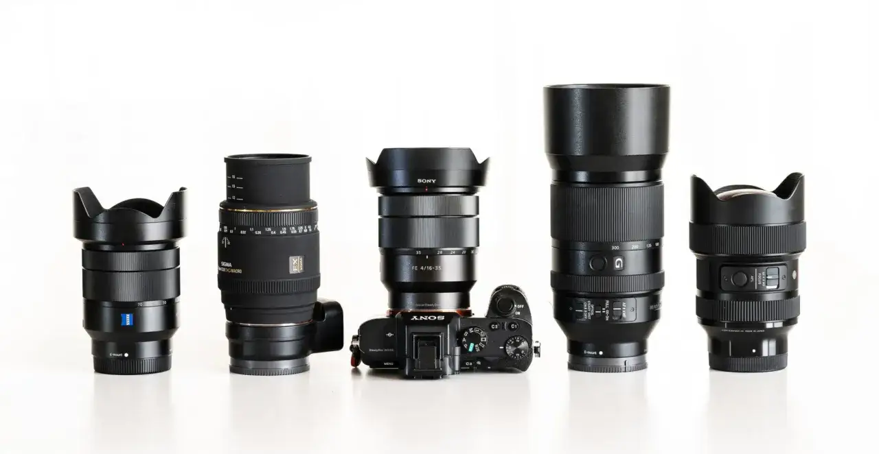 Różne obiektywy, w tym Sony FE 4/16-35, Sigma i Zeiss, obok aparatu Sony a6000. Jaki obiektyw do Sony a6000 wybrać?